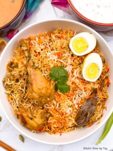 Chicken Biryani with chicken drumsticks and eggs on top.