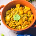 Potato edamame curry in an orange bowl.