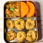 Spinach Medu Vada or Garelu with chicken curry and persimmon cut into slices in a lunchbots lunchbox.
