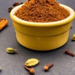 Garam masala in a yellow bowl with spices around it.