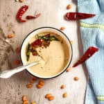 Peanut chutney in a bowl with tempering of Dried red chilies, curry leaves, mustard seeds, cumin seeds and urad dal.