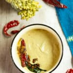 Pumpkin seed chutney in a bowl with the tadka of cumin seeds, mustard seeds, dried red chilies and curry leaves on top.