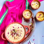 Sheer Khurma in a bowl and three glasses with nuts, dates and rose petals on top.