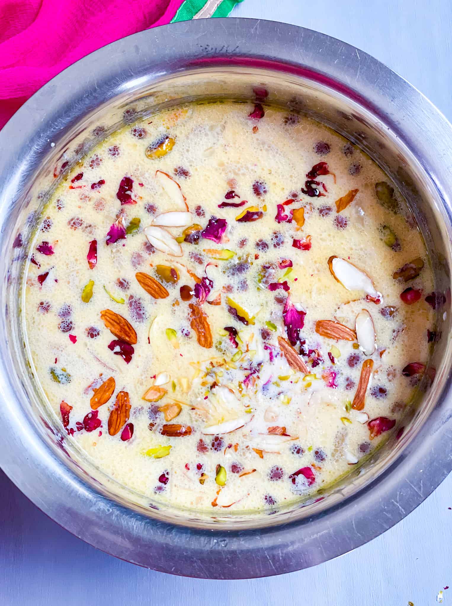 Sheer Khurma in a bowl with nuts, dates and rose petals on top.