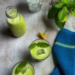 Mint buttermilk in glasses and bottle with ice cubes and mint leaves on top.