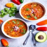 Quinoa chili in 2 bowls with a garnish of onions and cilantro.