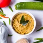 Zucchini chutney in a bowl with curry leaves on top.