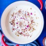 Instant Rabdi in a red dutch oven with chopped nuts and dried rose petals on top.