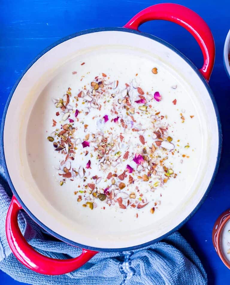Instant Rabdi in a red dutch oven with chopped nuts and dried rose petals on top.