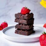 A stack of black bean brownie with strawberries on top.
