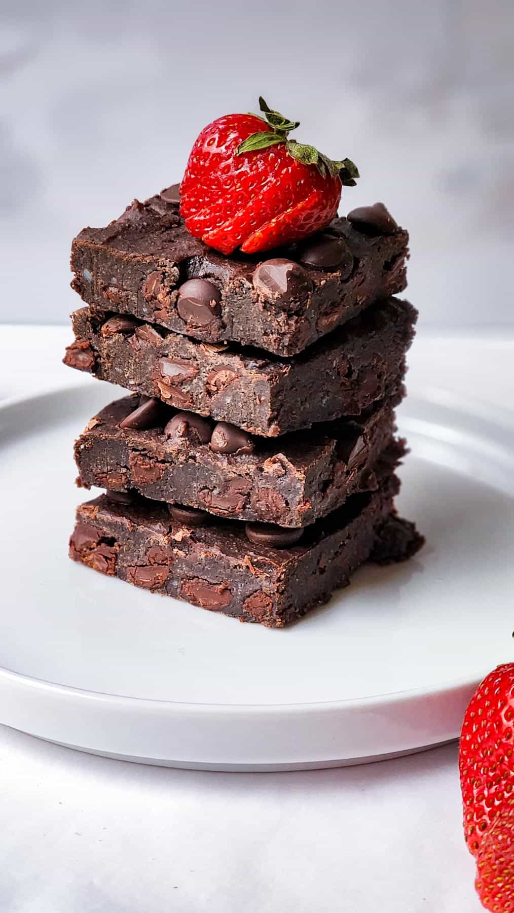 A stack of black bean brownie with strawberries on top.