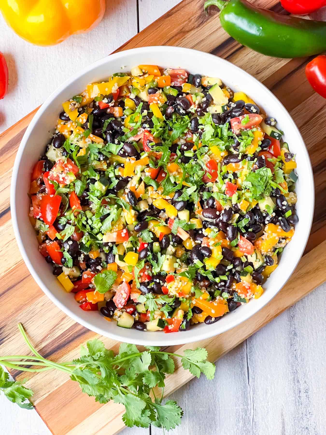 Black bean and hemp salad in a white bowl on a wooden chopping board.