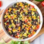 Black bean and hemp salad in a white bowl on a wooden chopping board.